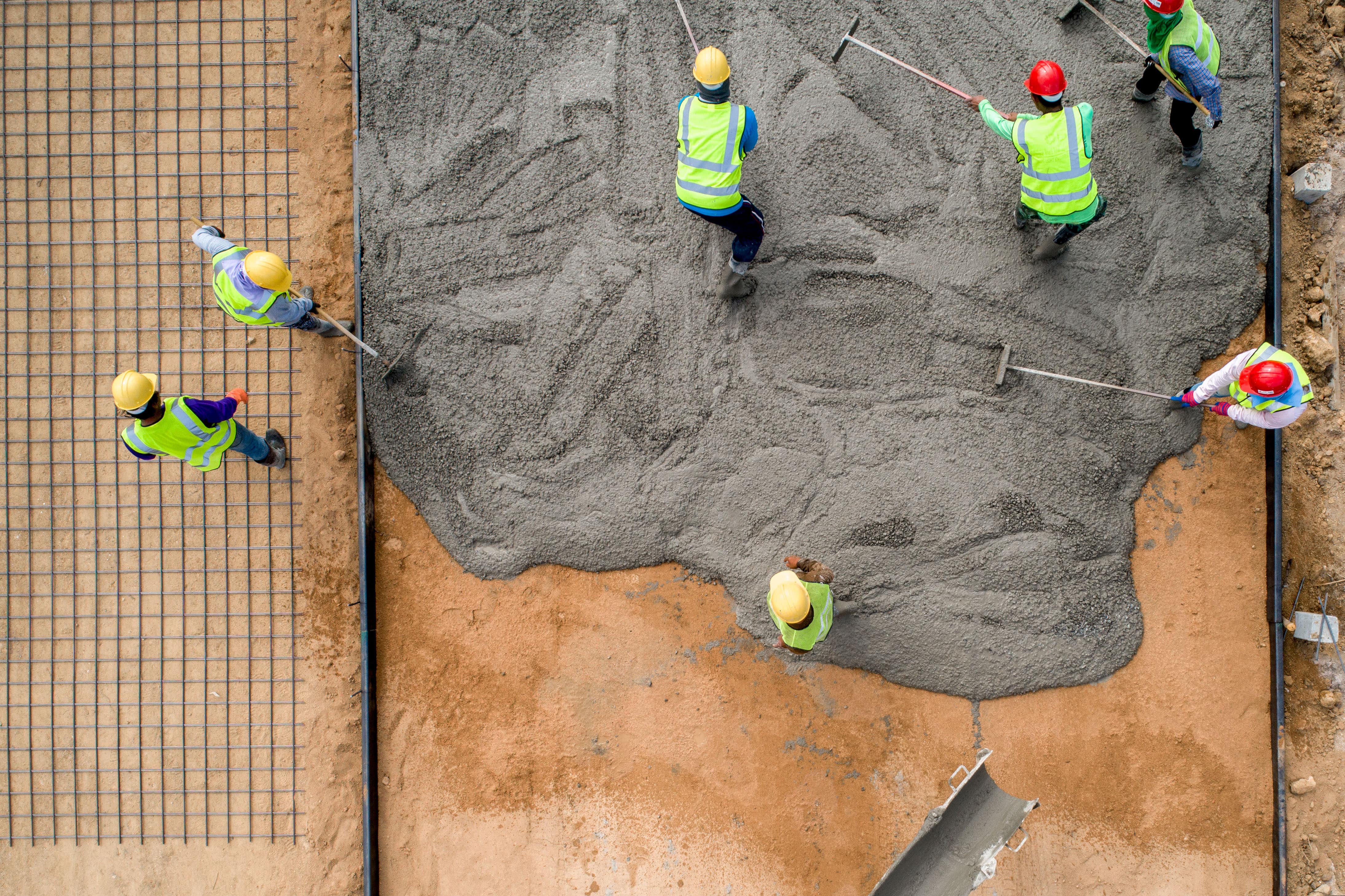 A construction worker pouring a wet concrete at road construction